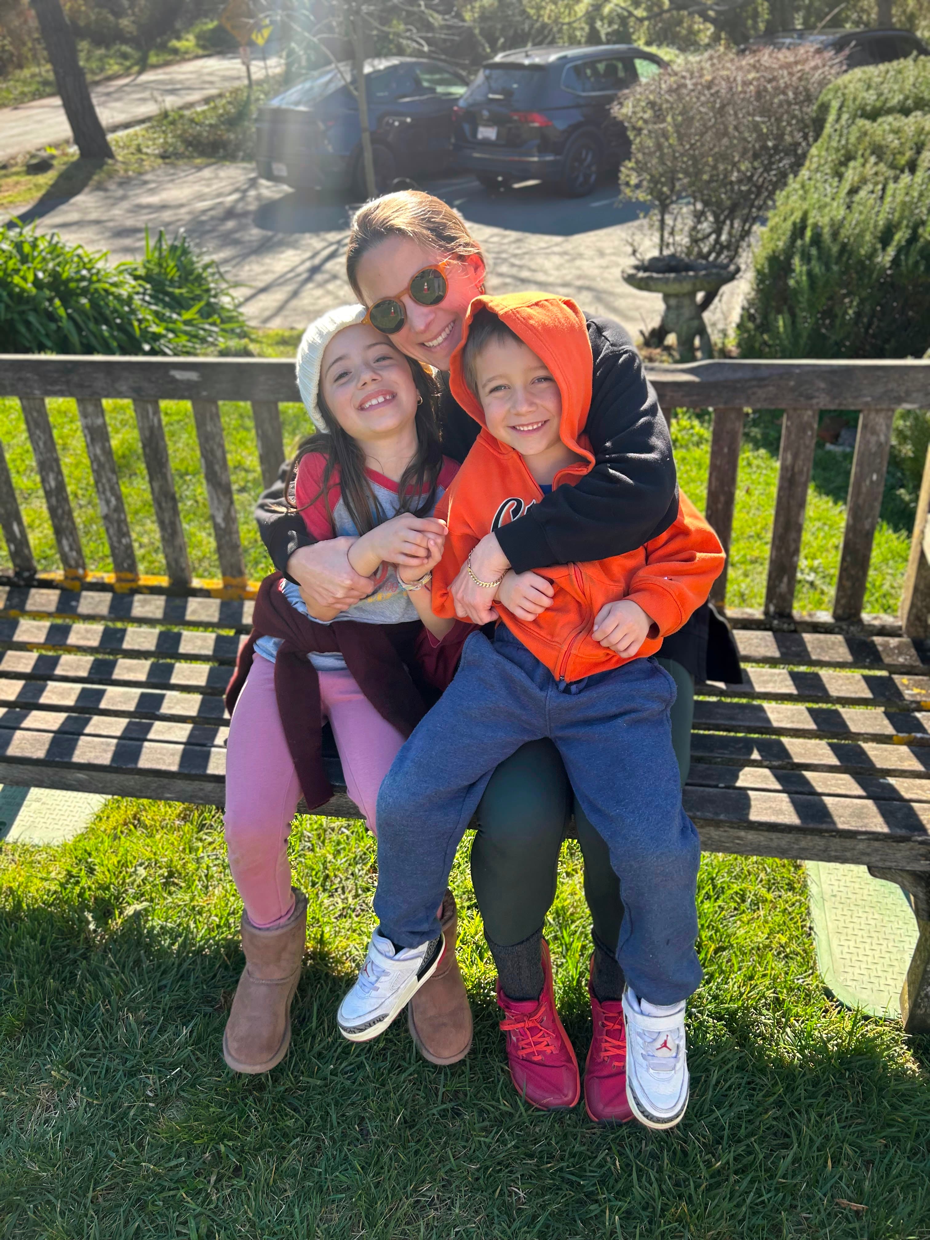 Sadie with two children sitting on a bench outdoors